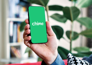 Person holding a smartphone displaying the Chime bank mobile app interface.