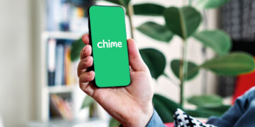 Person holding a smartphone displaying the Chime bank mobile app interface.