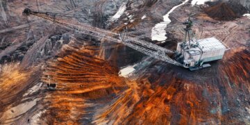 Aerial view of a large mining excavator on a site with earth and machinery.