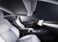 Interior view of a Tesla Model 3 featuring white leather seats and a central touchscreen display.
