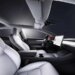 Interior view of a Tesla Model 3 featuring white leather seats and a central touchscreen display.