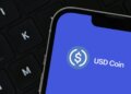 Close-up of a smartphone screen showing the USD Coin logo on a blue background.
