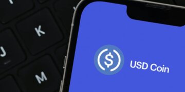 Close-up of a smartphone screen showing the USD Coin logo on a blue background.