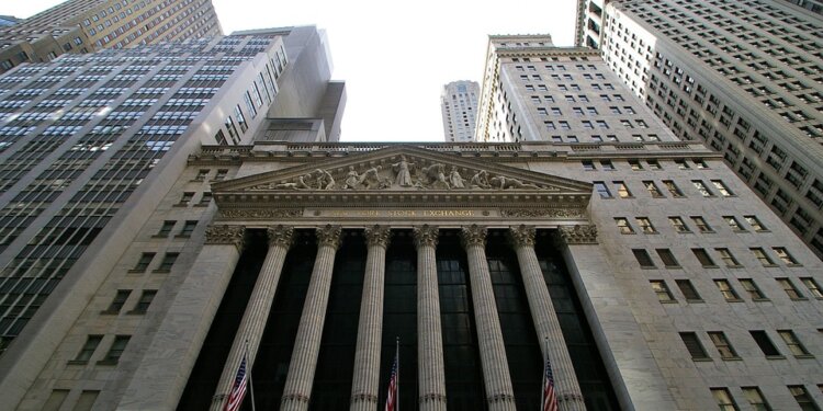 Facade of the New York Stock Exchange with columns and flags, viewed from below.