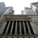 Facade of the New York Stock Exchange with columns and flags, viewed from below.