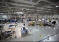 Interior view of a large manufacturing facility with various equipment and workstations.