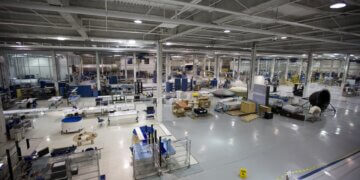 Interior view of a large manufacturing facility with various equipment and workstations.