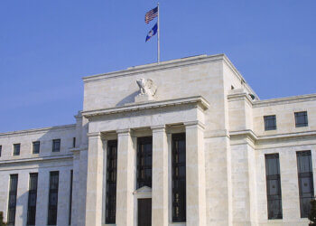 Exterior view of the Federal Reserve building featuring columns and flags.