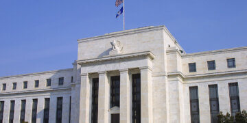 Exterior view of the Federal Reserve building featuring columns and flags.