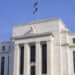 Exterior view of the Federal Reserve building featuring columns and flags.